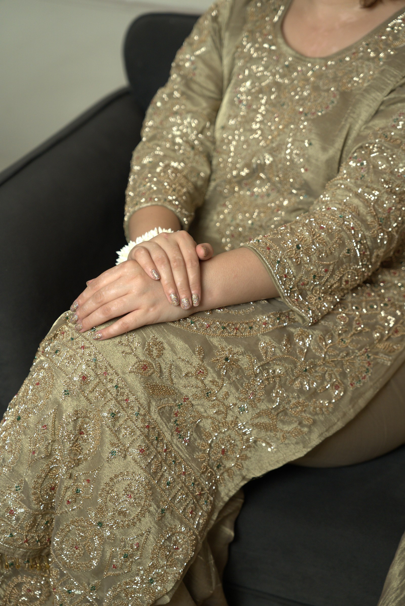 A closer view of the same olive-gold suit, showing the embroidery across the front and sleeve
