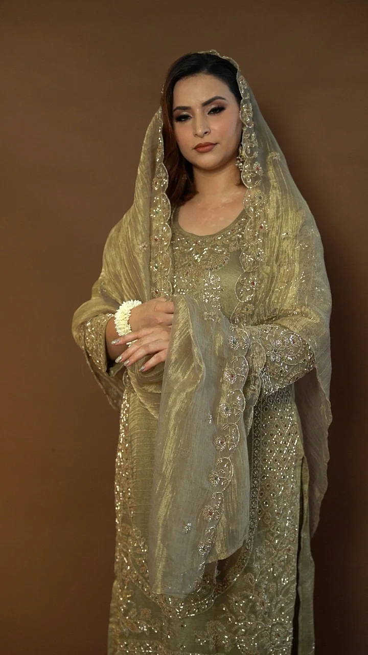 Olive-gold suit with a sheer dupatta, filmed against a warm brown backdrop